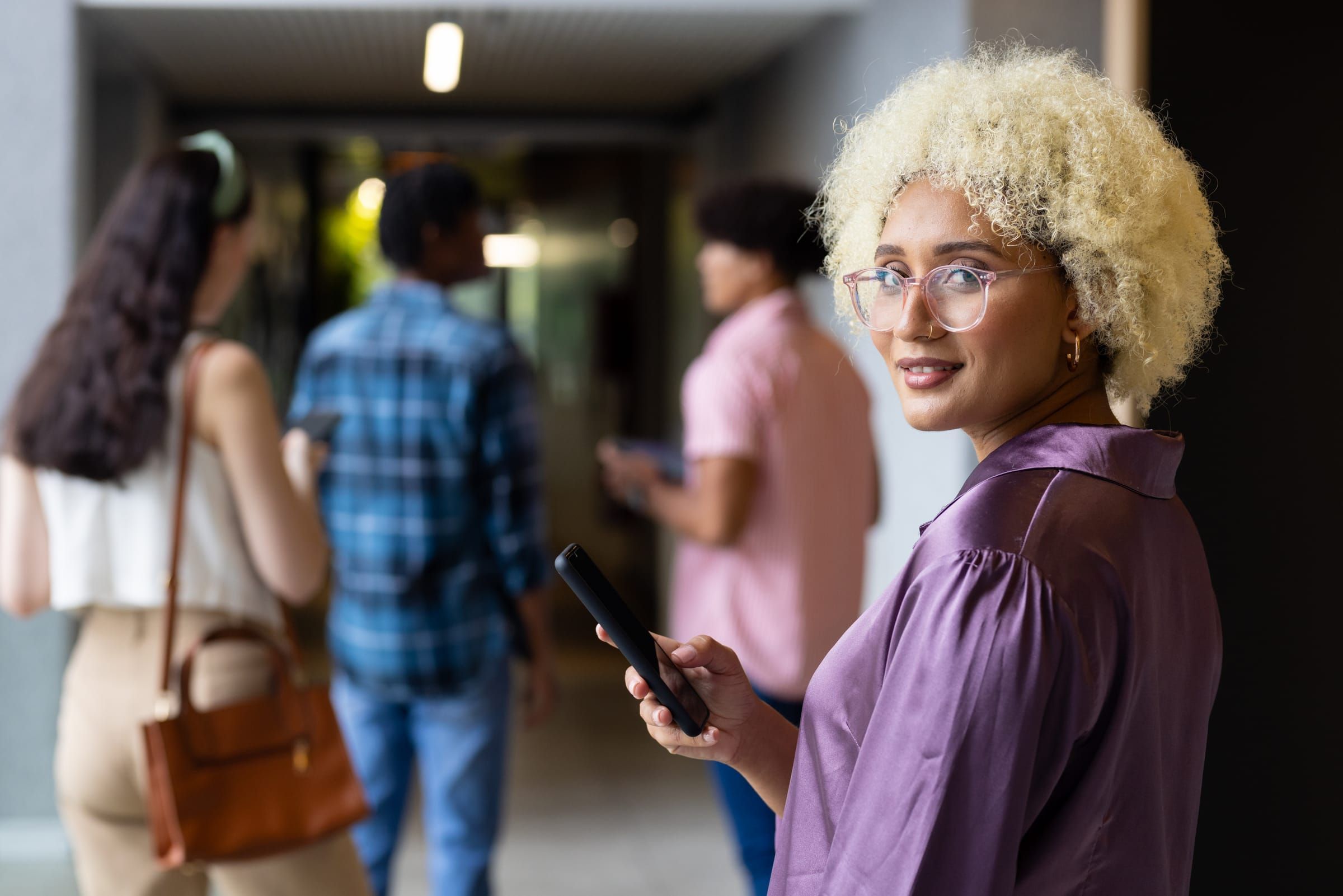 Community center staff member holding a smartphone in a busy lobby