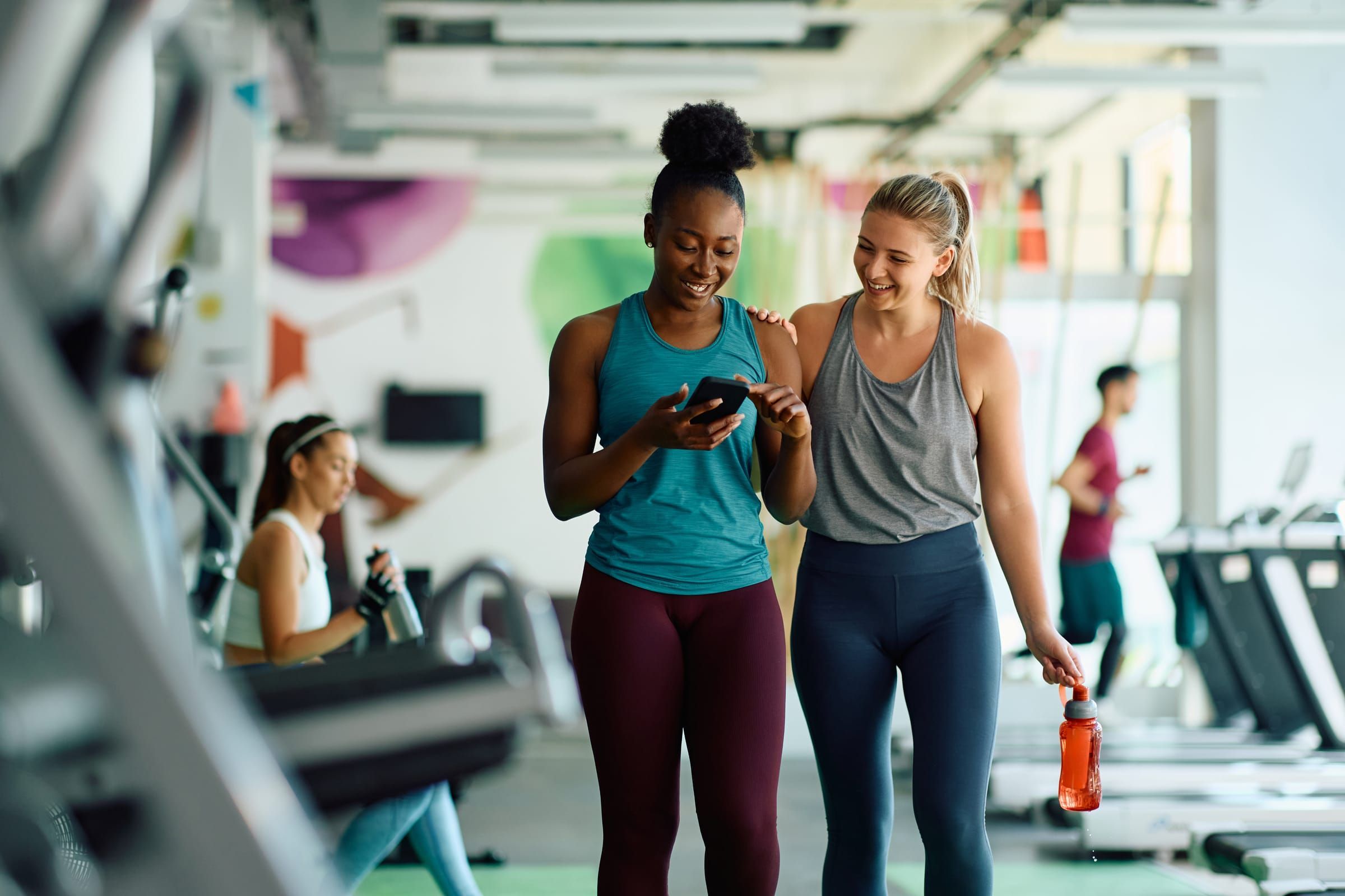 Two staff members reviewing a phone together on a community center fitness floor