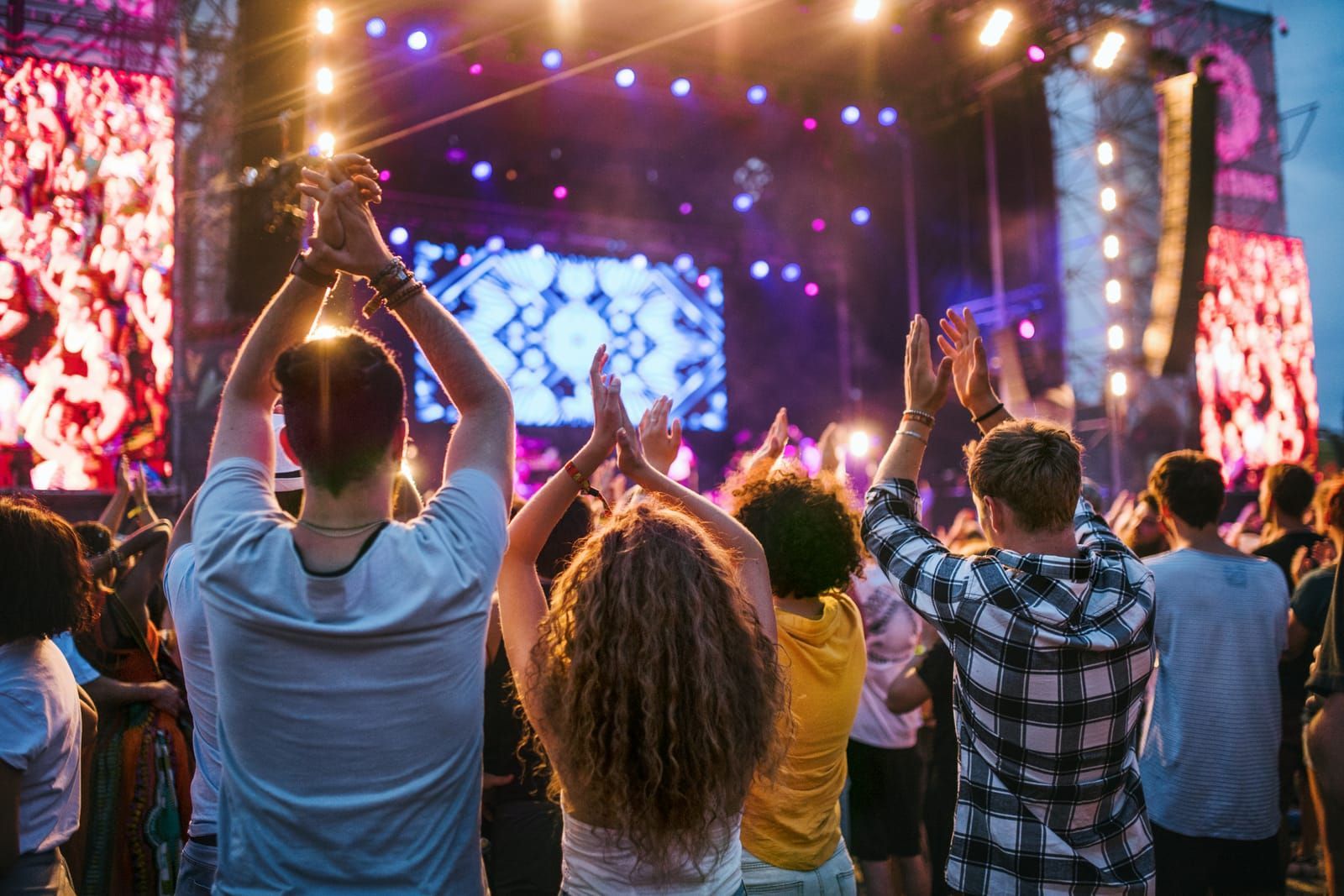 Crowd with raised hands at an outdoor concert stage