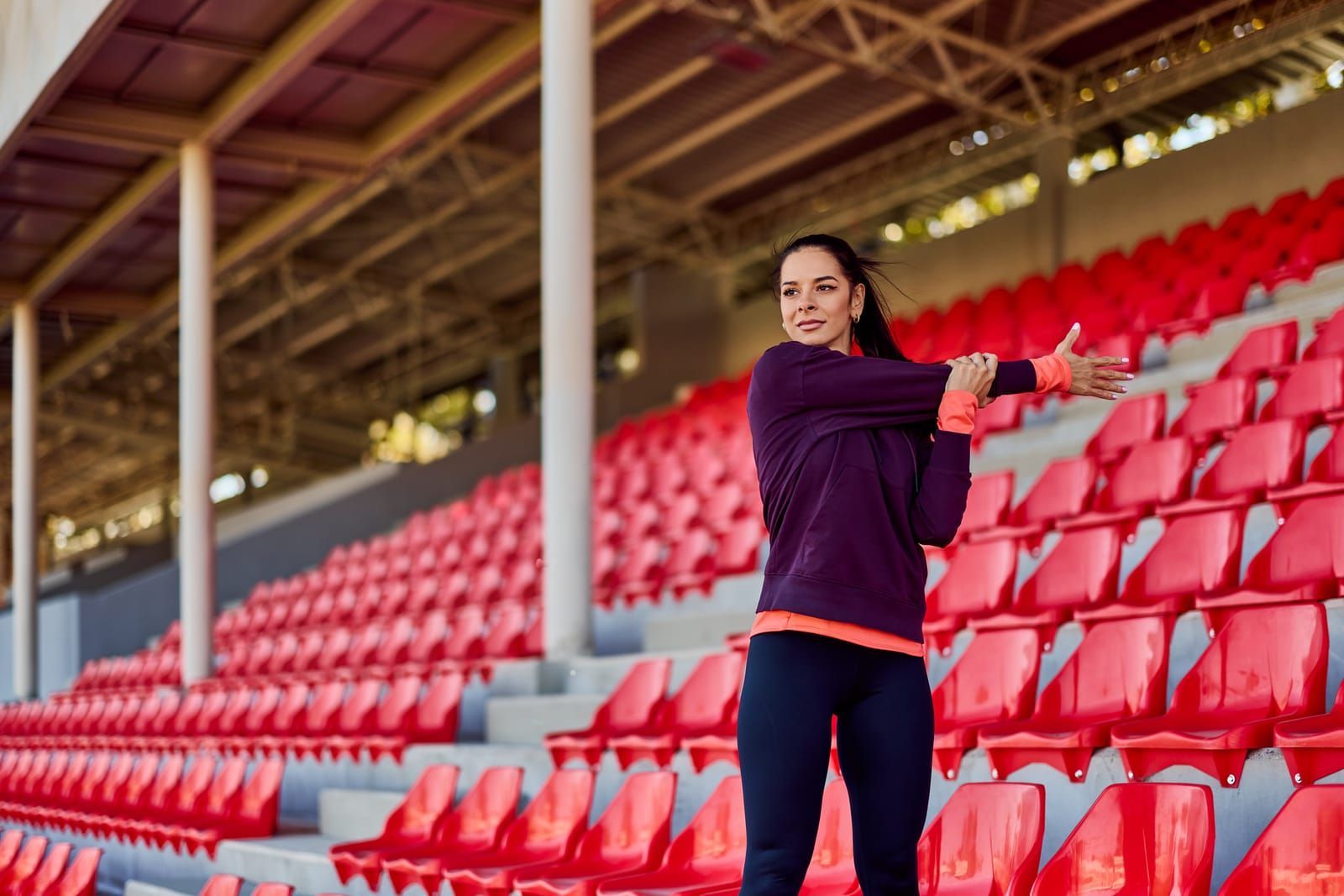 Person stretching among red stadium seats